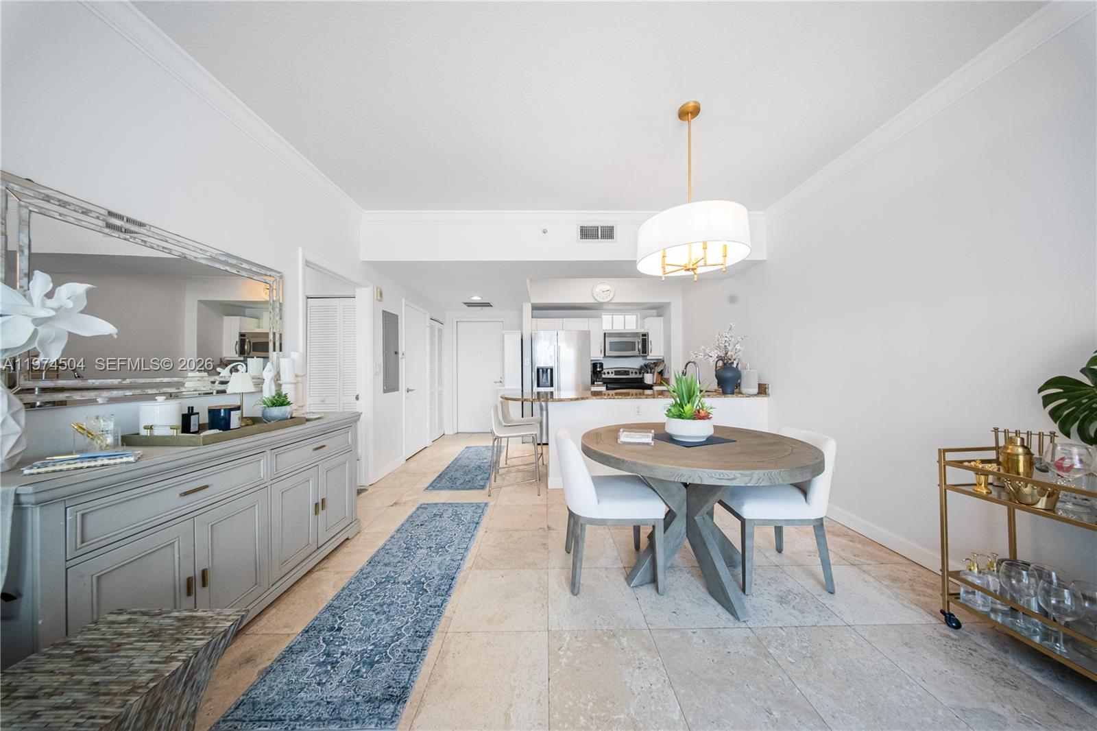 A dining area features a round wooden table, white chairs, and a gray sideboard — 7290 SW 90th St # 308, Miami FL 33156, MIAMI, FL