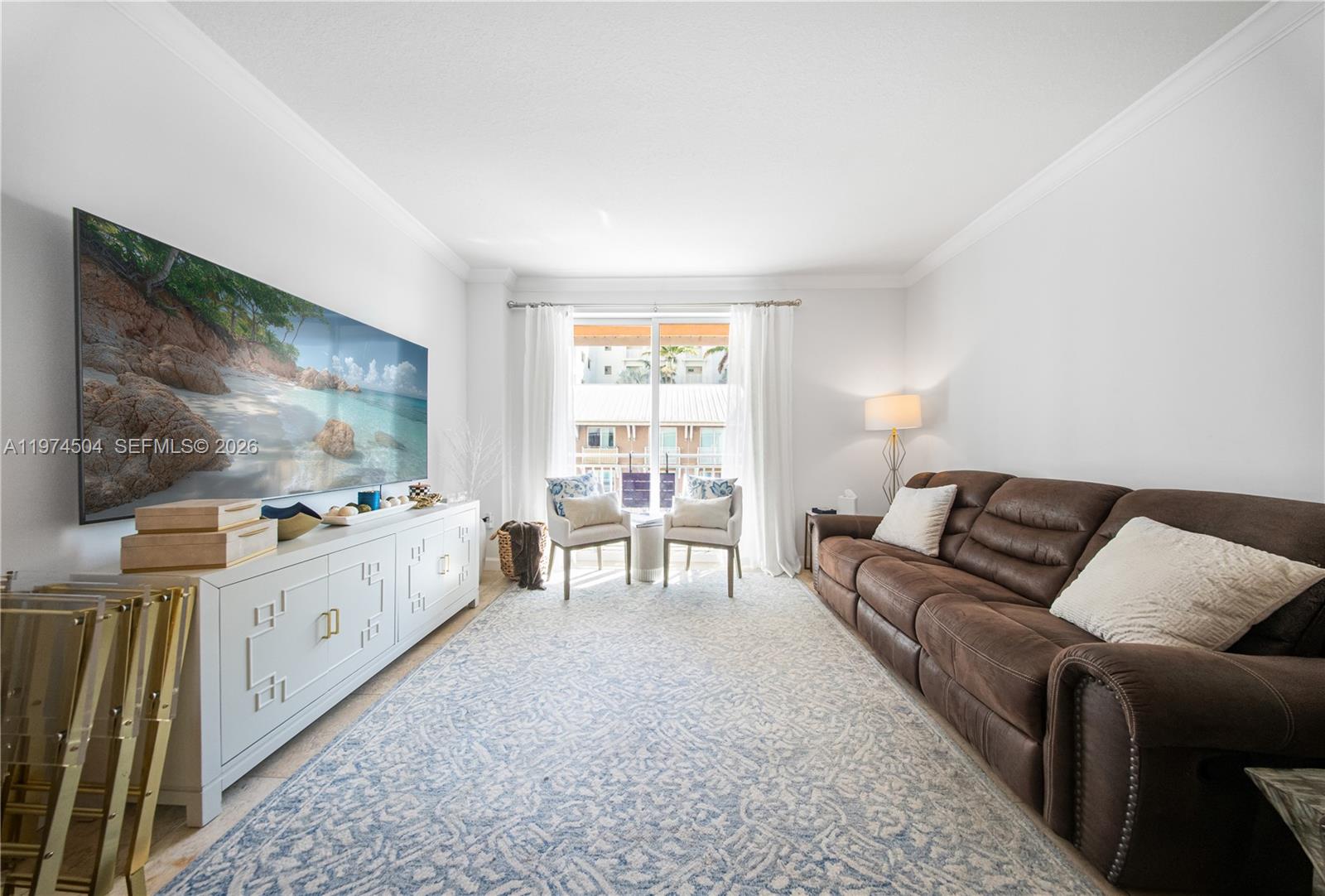 A living room features a brown leather sofa, a white media console, and a patterned rug — 7290 SW 90th St # 308, Miami FL 33156, MIAMI, FL