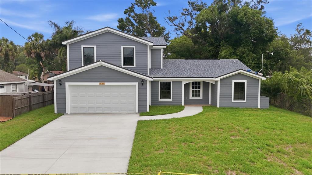 A two-story gray house with a two-car garage and a concrete driveway sits on grass — 1615 31ST AVENUE E, BRADENTON, FL