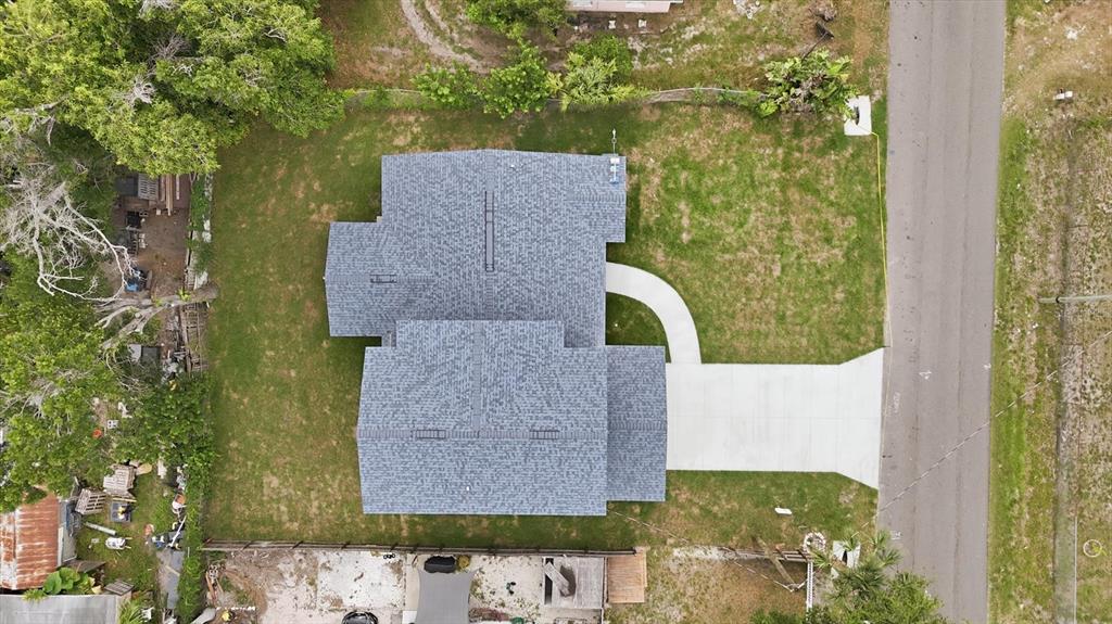 An aerial view shows a house with a gray shingled roof, driveway, and surrounding lawn — 1615 31ST AVENUE E, BRADENTON, FL