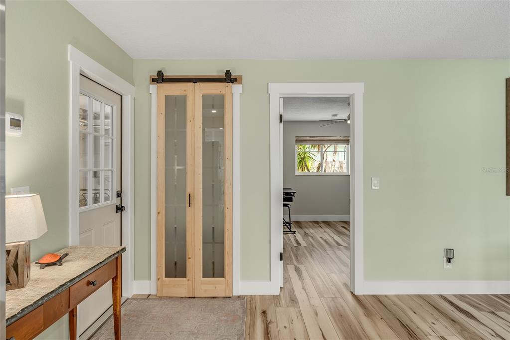 A light green room features a wooden sliding barn door, a white door, and a doorway — 390 URSA AVENUE, MERRITT ISLAND, FL