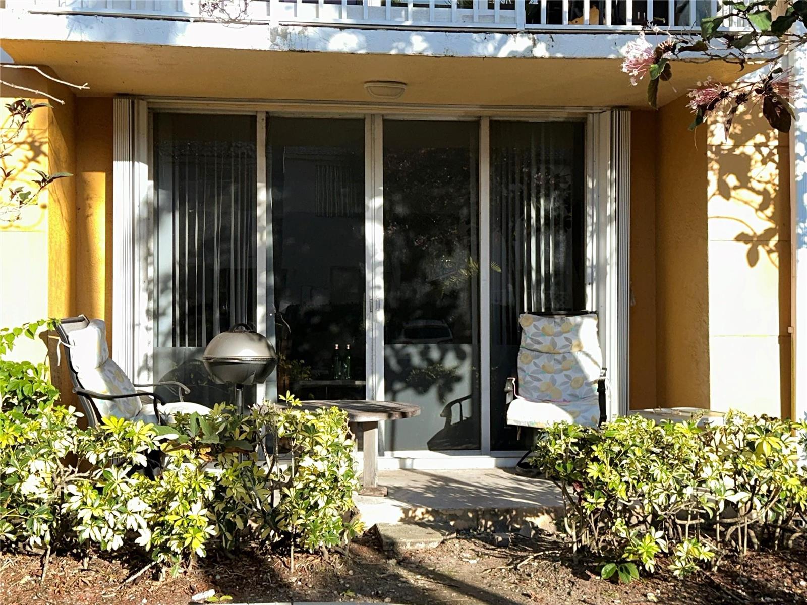 A patio features a sliding glass door, two chairs, a small table, and a grill — 1450 SE 3rd Avenue # 107, Dania Beach FL 33004, DANIA BEACH, FL