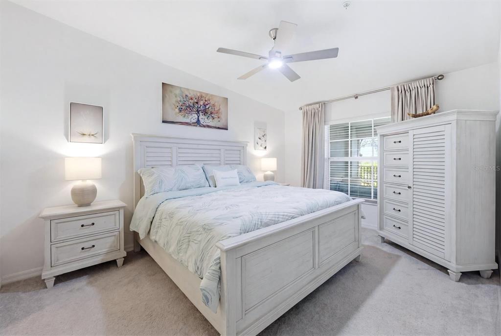 A bedroom features a white wooden bed frame, matching nightstand, and a tall armoire — 12580 GALAPAGOS COURT UNIT #204, VENICE, FL