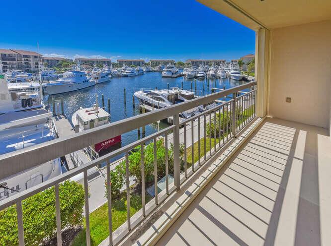 A balcony overlooks a marina filled with numerous yachts and boats on a sunny day — 2601 Marina Isle Way # 303, Jupiter FL 33477, JUPITER, FL