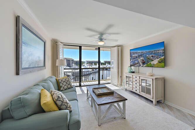 A living room with a light blue sofa, wooden coffee table, and a marina view — 2601 Marina Isle Way # 303, Jupiter FL 33477, JUPITER, FL