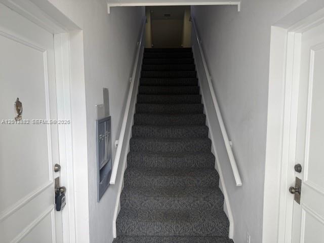 A carpeted staircase leads upward between two white doors in a narrow hallway — 170 Cypress Club Dr # 733, Pompano Beach FL 33060, POMPANO BEACH, FL