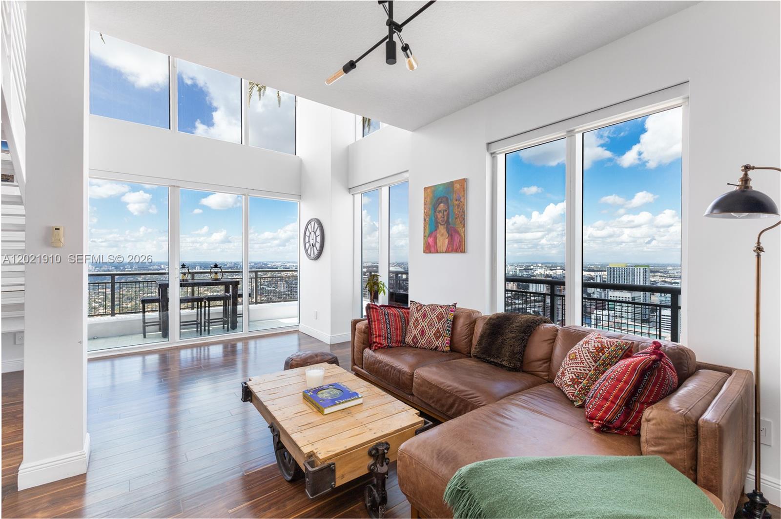 A living room features a leather sectional, wooden coffee table, and floor-to-ceiling windows with views — 60 SW 13th St # 4613, Miami FL 33130, MIAMI, FL