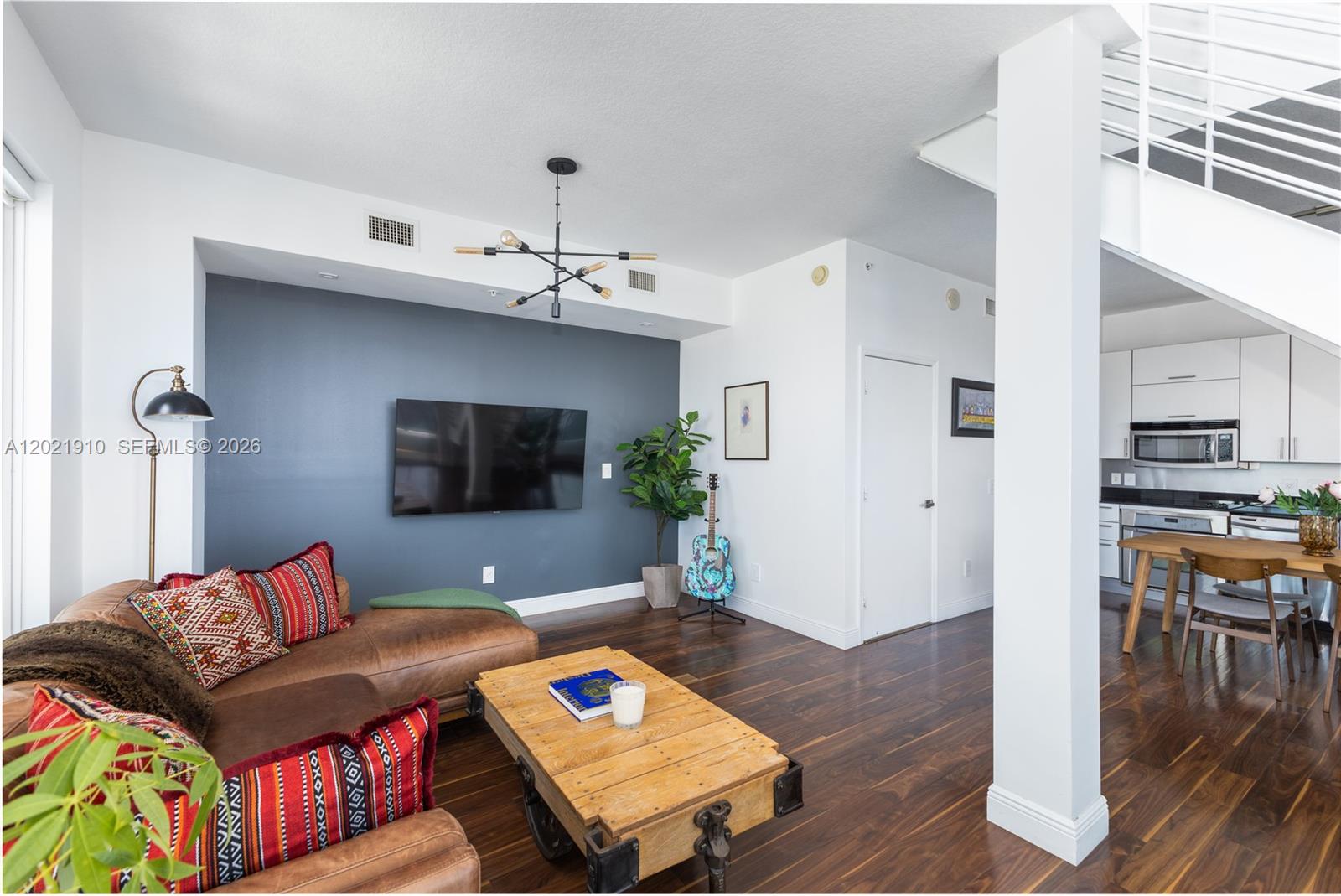 A living room with a leather sectional, blue accent wall, and adjacent kitchen area — 60 SW 13th St # 4613, Miami FL 33130, MIAMI, FL