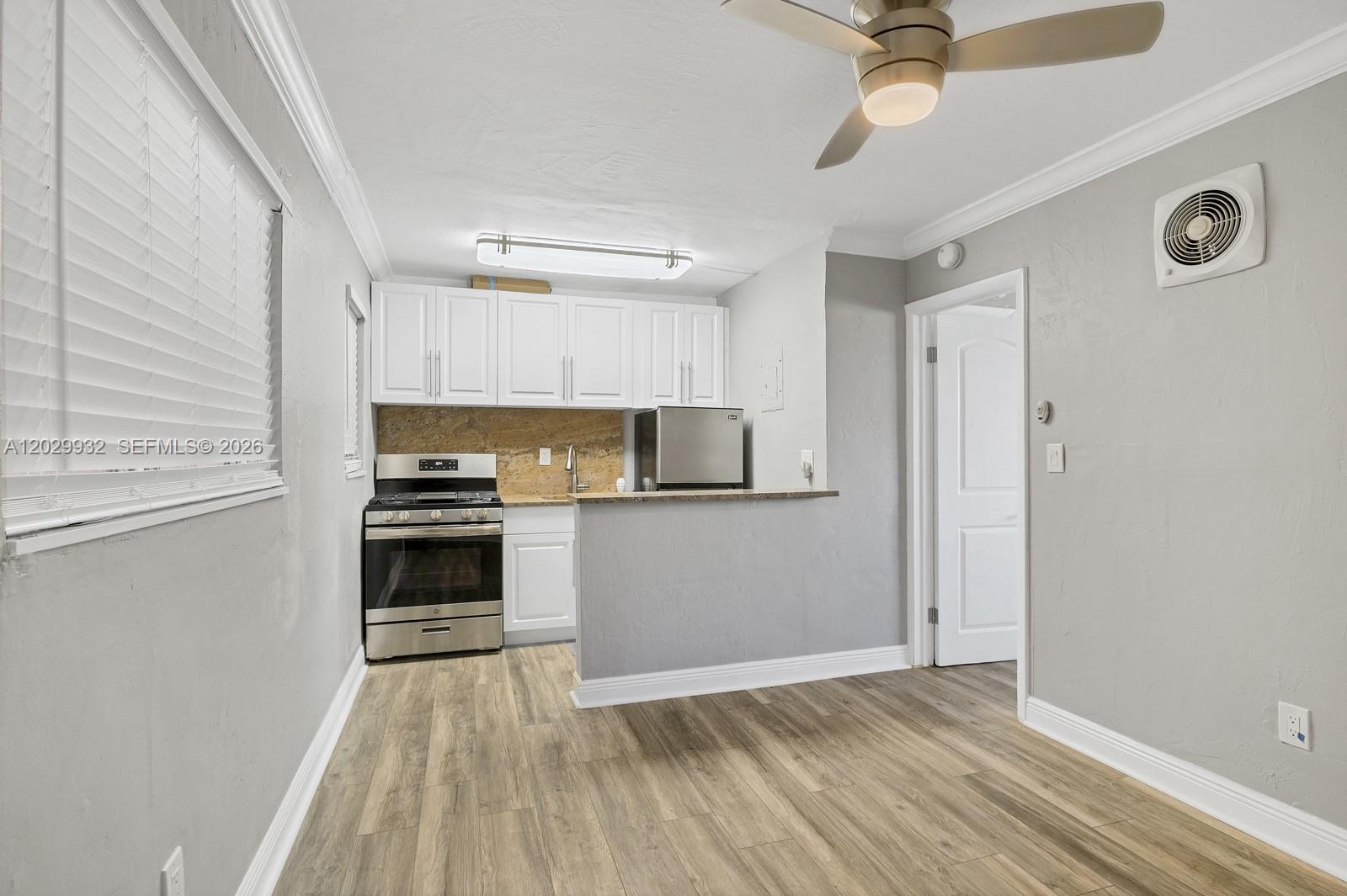 A kitchen features white cabinets, stainless steel appliances, and a peninsula in a gray room — 1014 Salzedo St # 211, Coral Gables FL 33134, CORAL GABLES, FL
