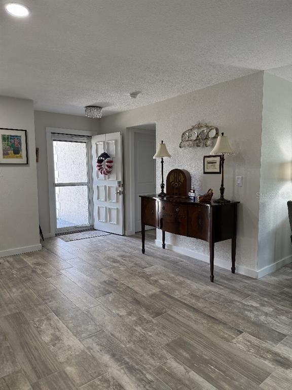A room with wood-look tile flooring features an entryway door and a dark wood sideboard — 3323 TEESIDE DRIVE, NEW PORT RICHEY, FL