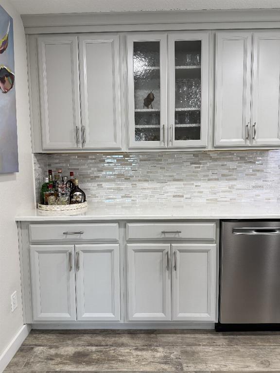 A kitchen area features light gray cabinets, a glass-tiled backsplash, and a stainless steel dishwasher — 3323 TEESIDE DRIVE, NEW PORT RICHEY, FL