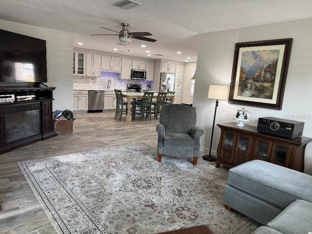 An open-concept living room flows into a kitchen with white cabinets and a center island — 3323 TEESIDE DRIVE, NEW PORT RICHEY, FL