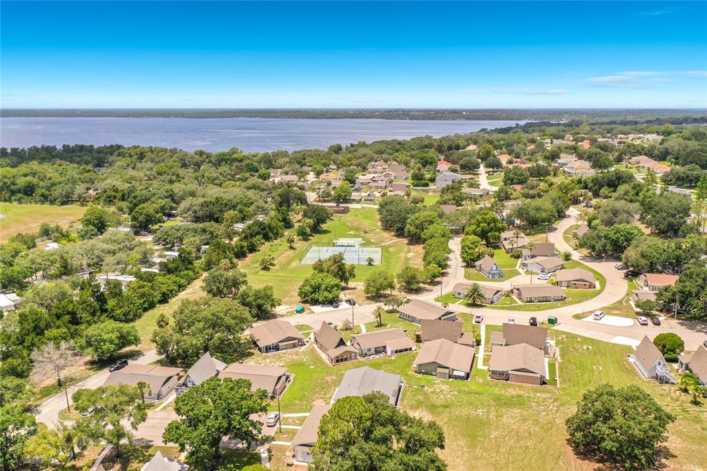 An aerial view shows a residential neighborhood with houses, a tennis court, and a lake — 10301 US HIGHWAY 27 UNIT 22, CLERMONT, FL