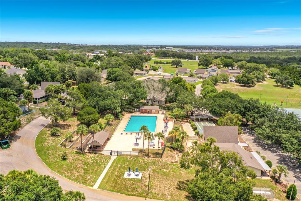 An aerial view shows a swimming pool, tennis courts, and surrounding residential buildings with trees — 10301 US HIGHWAY 27 UNIT 22, CLERMONT, FL