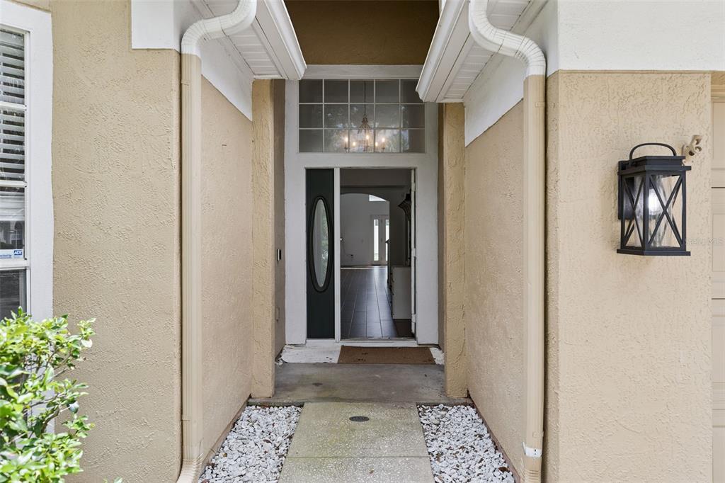 The exterior entryway features a tan stucco facade, a dark front door, and a lantern light — 7800 SAINT GILES PLACE, ORLANDO, FL