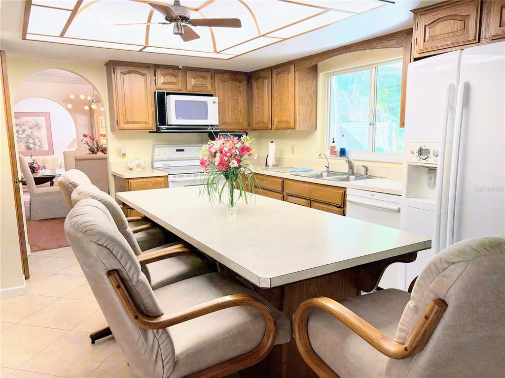 A kitchen features wood cabinets, a large central island, and a white refrigerator — 30 SABLE COURT, WINTER SPRINGS, FL