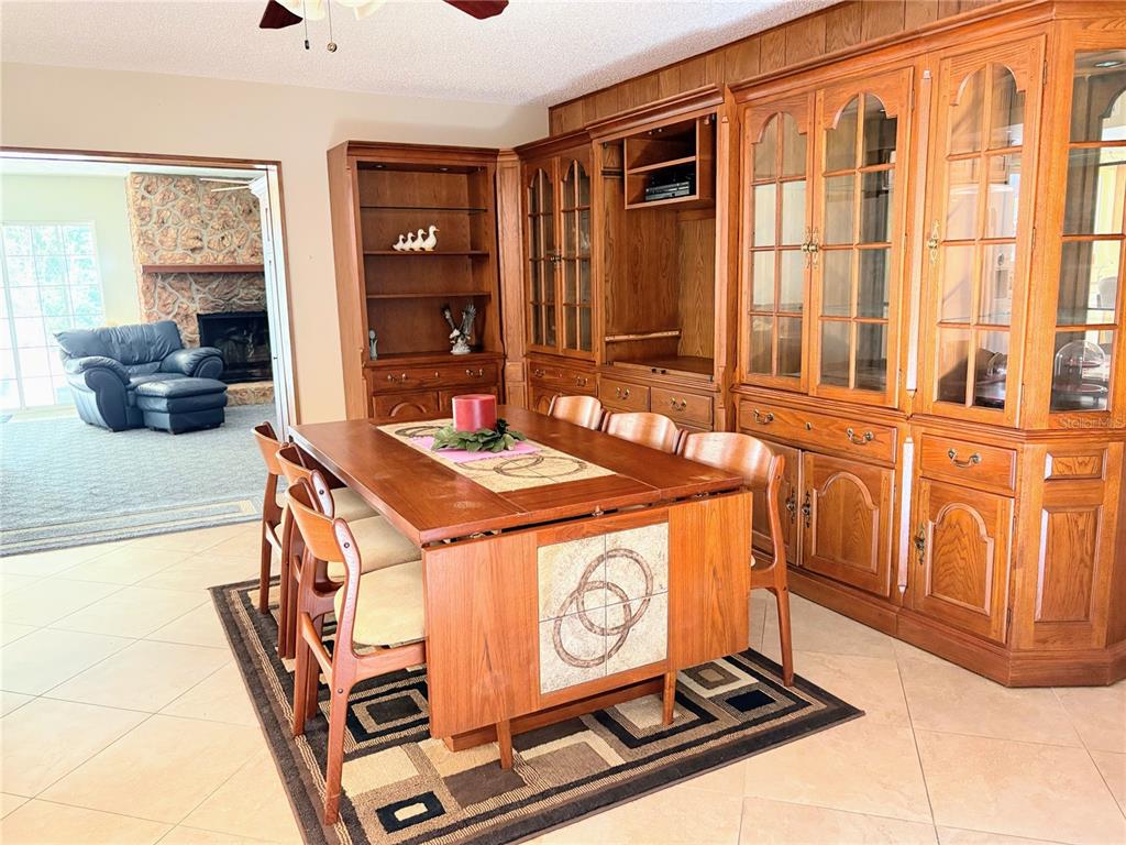 A dining room features a wooden table and hutch set on a patterned area rug — 30 SABLE COURT, WINTER SPRINGS, FL