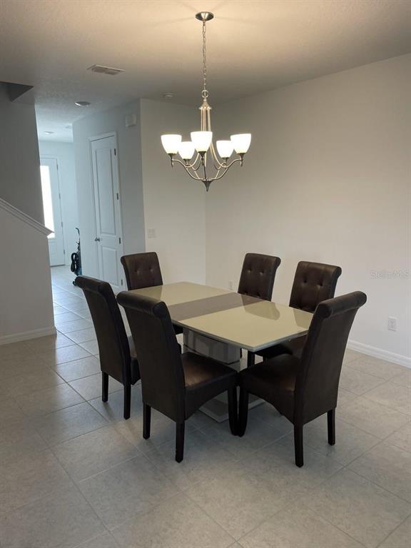 A dining area features a rectangular table with six tufted chairs under a chandelier — 1731 SANIBEL DR, DAVENPORT, FL