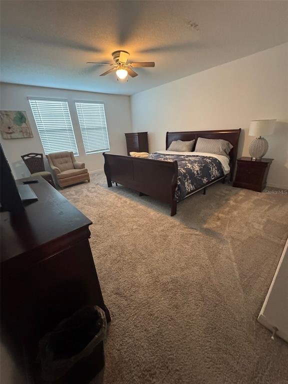 A bedroom features a dark wood bed frame, matching furniture, and beige carpeting — 1731 SANIBEL DR, DAVENPORT, FL