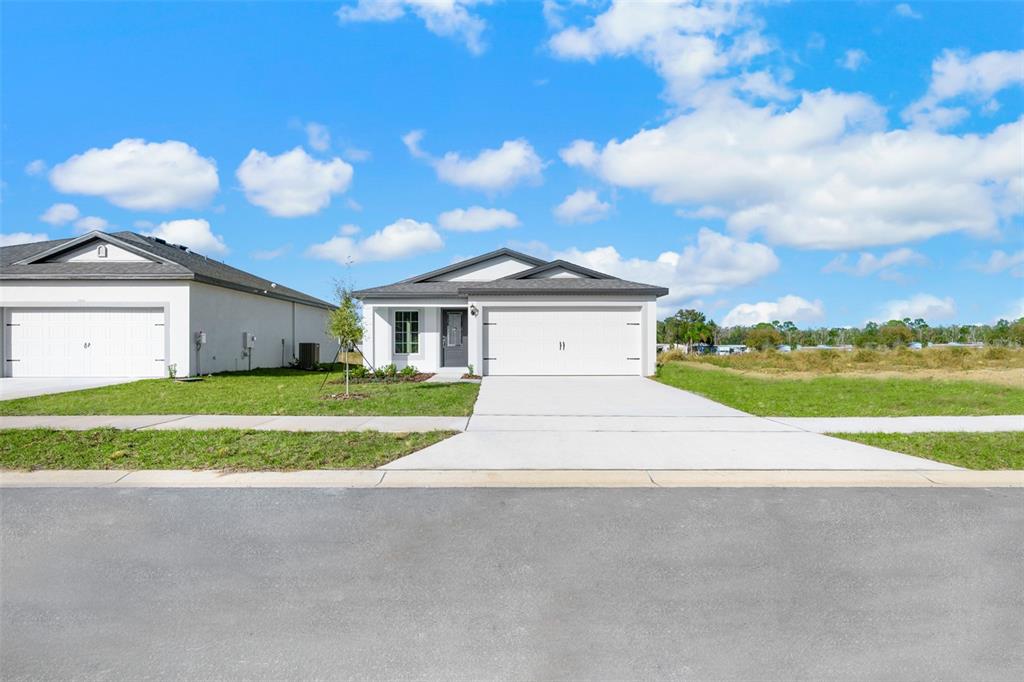 A single-story suburban house with a two-car garage and a concrete driveway — 13331 TULA LOOP, ASTATULA, FL