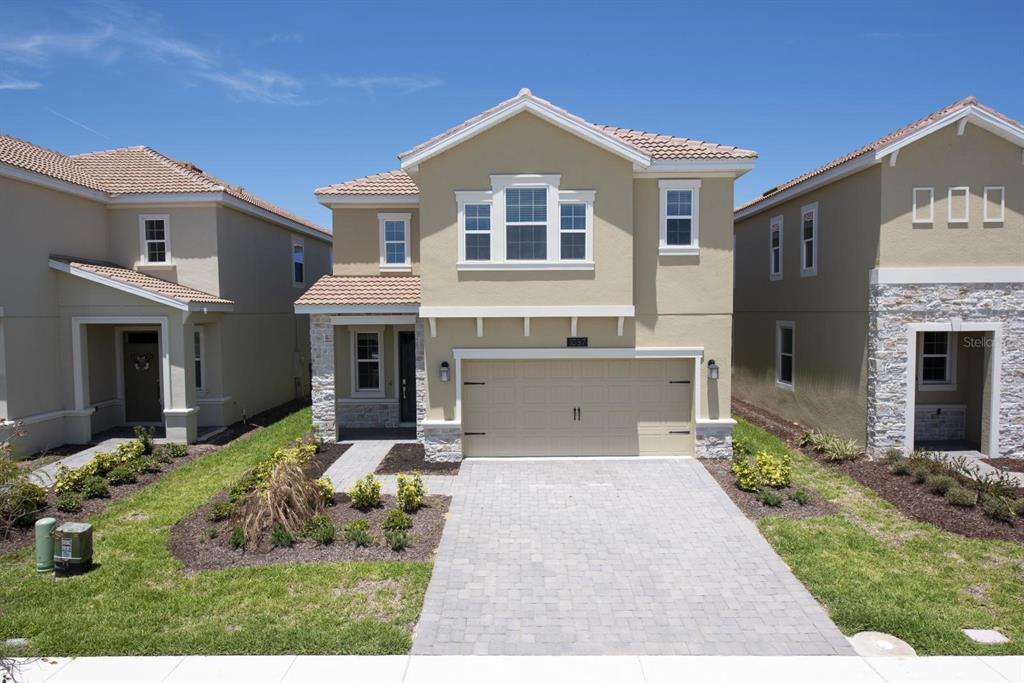 A two-story suburban house with a tan stucco exterior, tile roof, and a paved driveway — 1037 BLACKWOLF RUN ROAD, DAVENPORT, FL