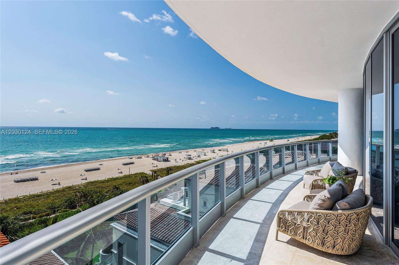 A curved balcony with glass railings overlooks a sandy beach and the ocean — 5959 Collins Ave # 807, Miami Beach FL 33140, MIAMI BEACH, FL