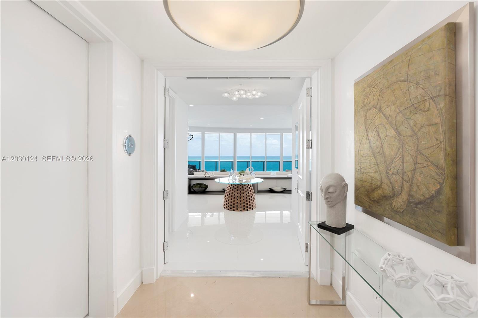 A bright entryway with white floors leads to a living area overlooking the ocean — 5959 Collins Ave # 807, Miami Beach FL 33140, MIAMI BEACH, FL