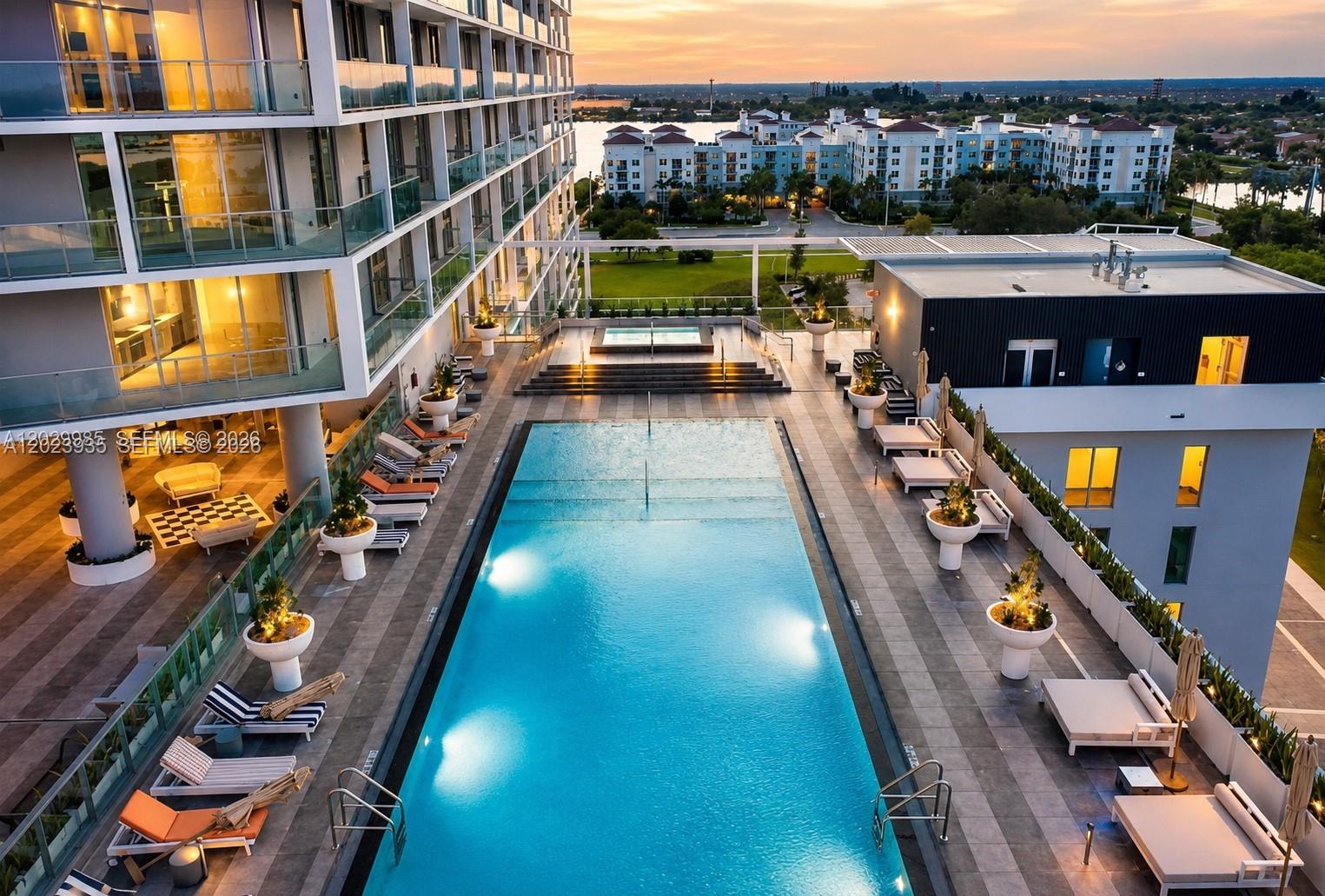 An elevated view of a rectangular swimming pool surrounded by lounge chairs and potted plants — 2000 Metropica Way # 1408, Sunrise FL 33323, SUNRISE, FL