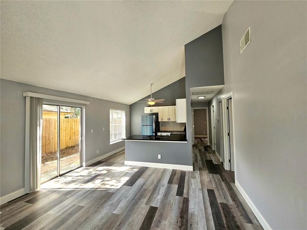 An open-concept living area features vaulted ceilings, gray walls, wood-look flooring, and a kitchen peninsula — 2668 MEGAN COURT, PALM HARBOR, FL