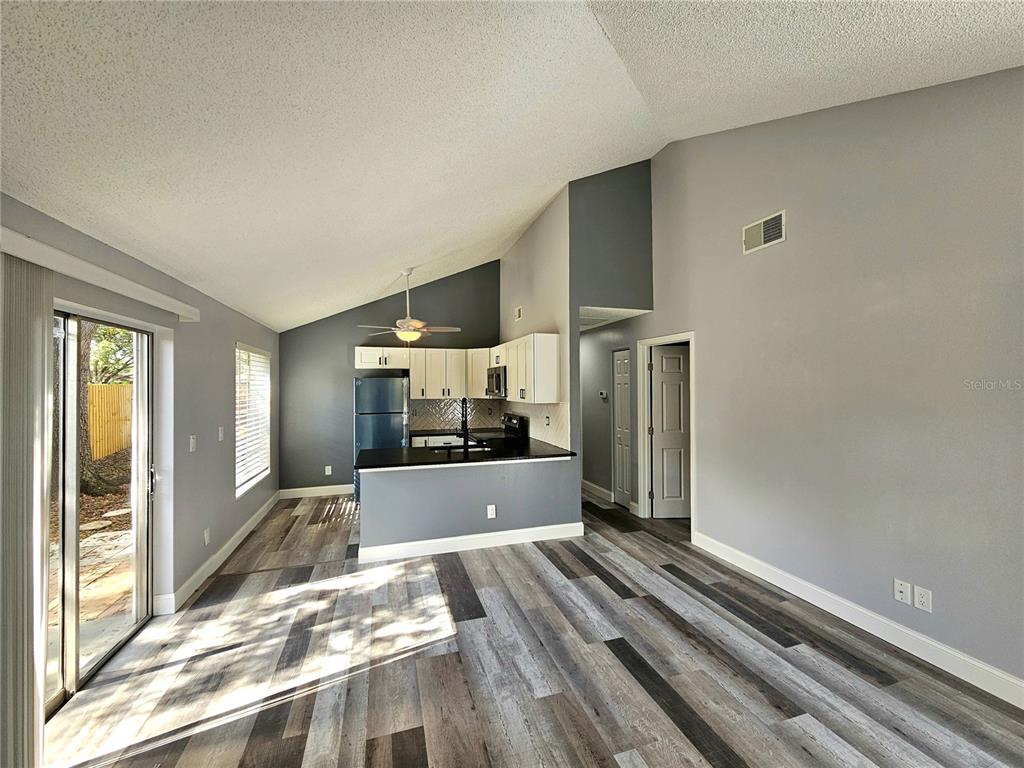 A kitchen with white cabinets and a dark island opens into a living area — 2668 MEGAN COURT, PALM HARBOR, FL
