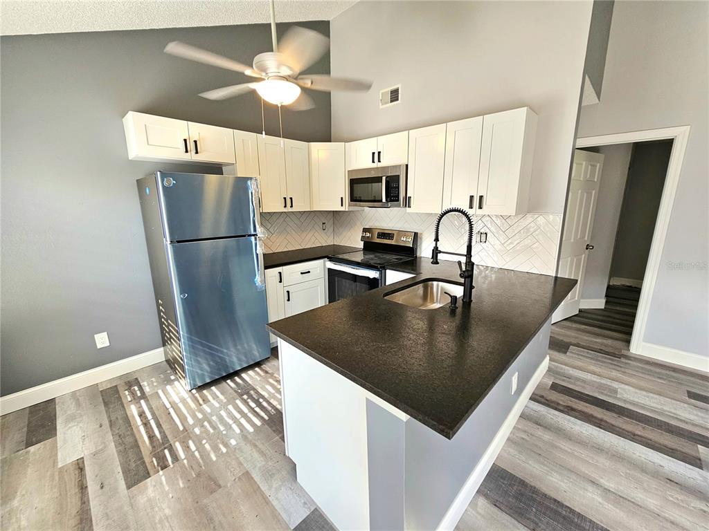 A kitchen features white cabinets, dark countertops, stainless steel appliances, and a kitchen island — 2668 MEGAN COURT, PALM HARBOR, FL