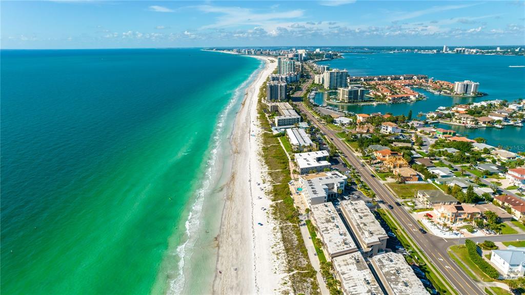 An aerial view shows a sandy beach along turquoise water next to coastal residential buildings — 2900 GULF BOULEVARD UNIT 204, BELLEAIR BEACH, FL