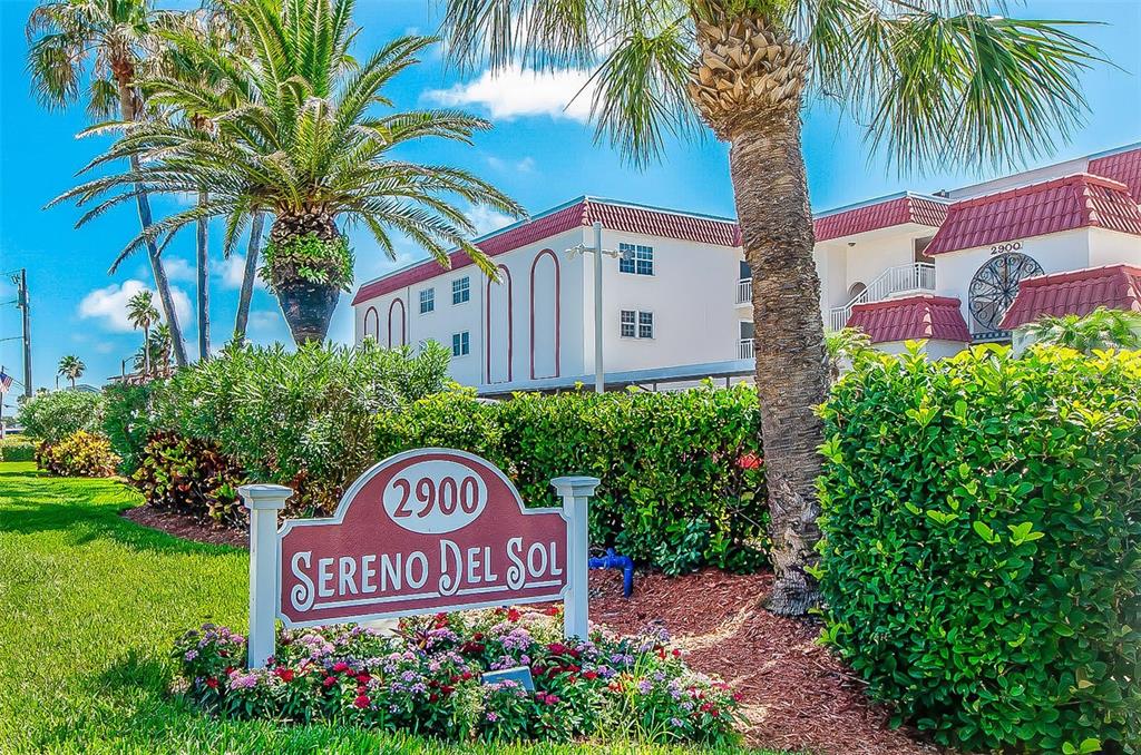 A sign for Sereno Del Sol stands in front of a multi-story apartment building — 2900 GULF BOULEVARD UNIT 204, BELLEAIR BEACH, FL
