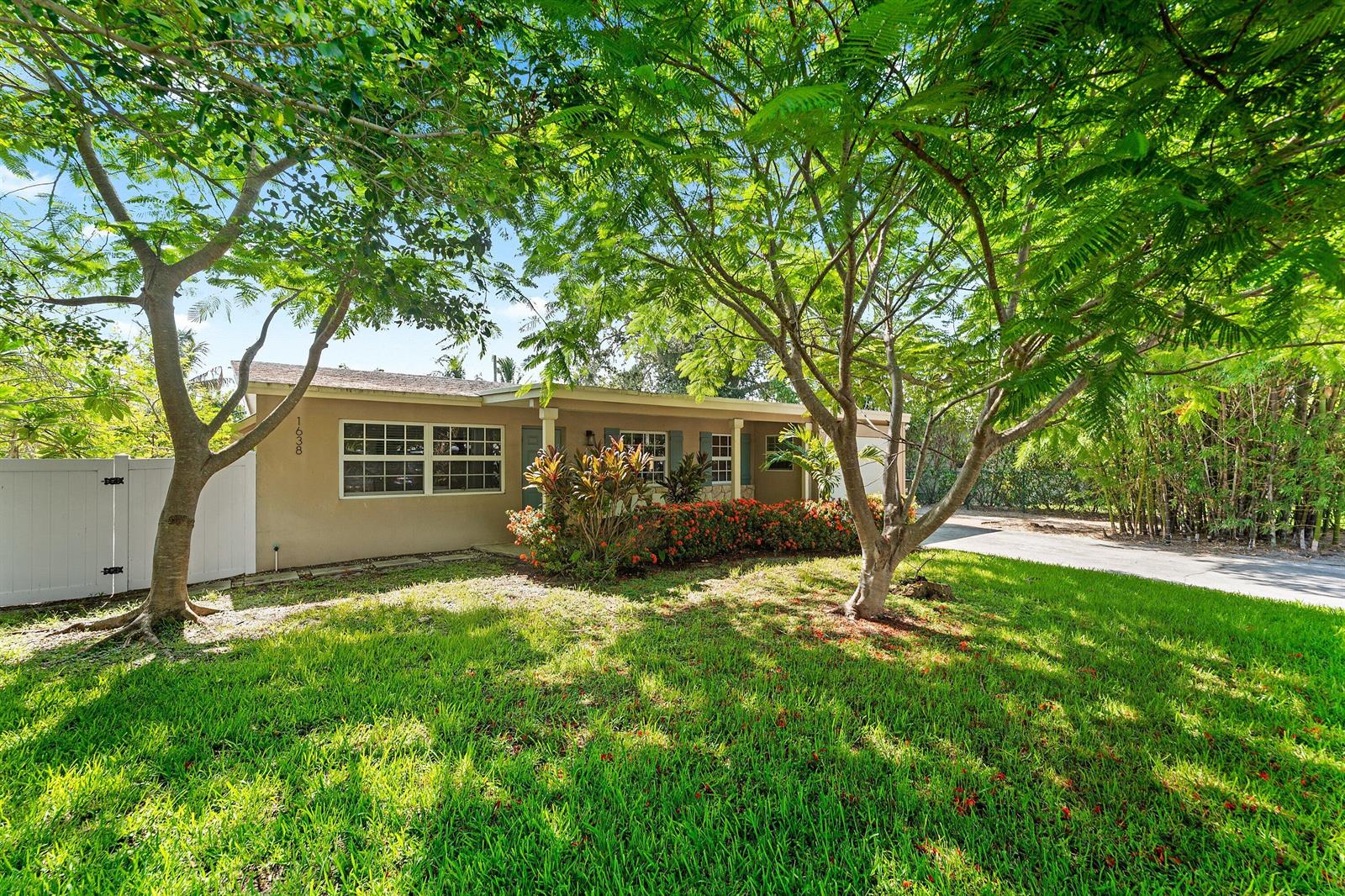 A single-story house with a tan exterior, white trim, and mature trees in the front yard — 1638 NE 3rd Avenue, Delray Beach FL 33444, DELRAY BEACH, FL