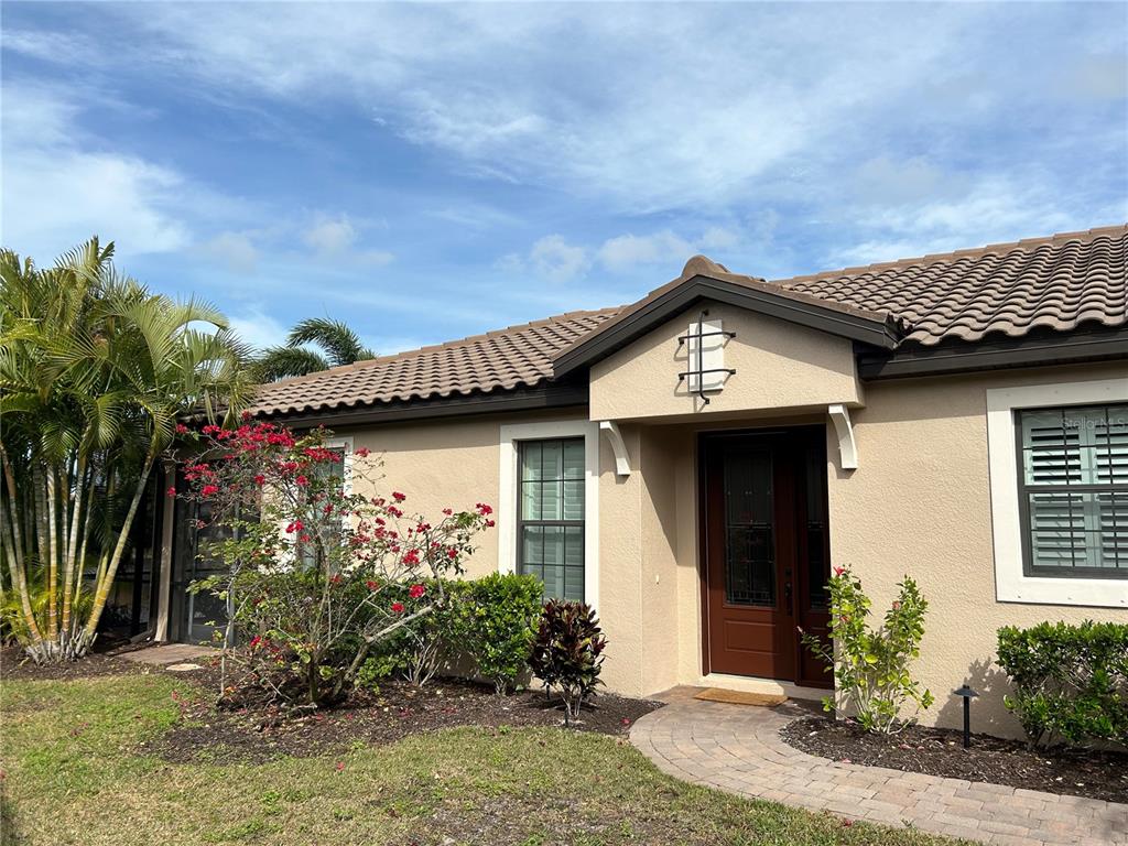 A living room with dark wood floors, a tray ceiling, and sliding glass doors — 13241 TORRESINA TERRACE, BRADENTON, FL