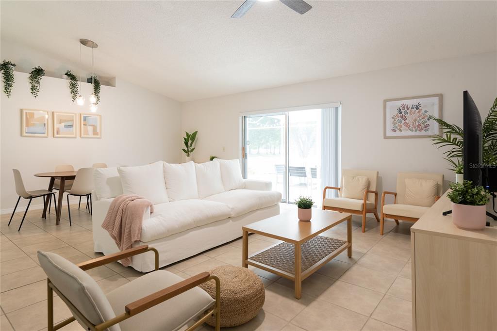 A living room with a white sofa, coffee table, armchairs, and a dining area — 1085 INDIAN RIDGE TRL E, KISSIMMEE, FL