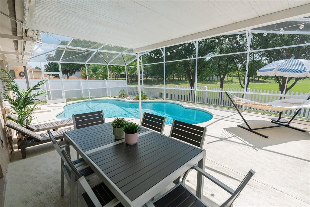 A screened-in patio features a dining set, a swimming pool, and a hammock — 1085 INDIAN RIDGE TRL E, KISSIMMEE, FL