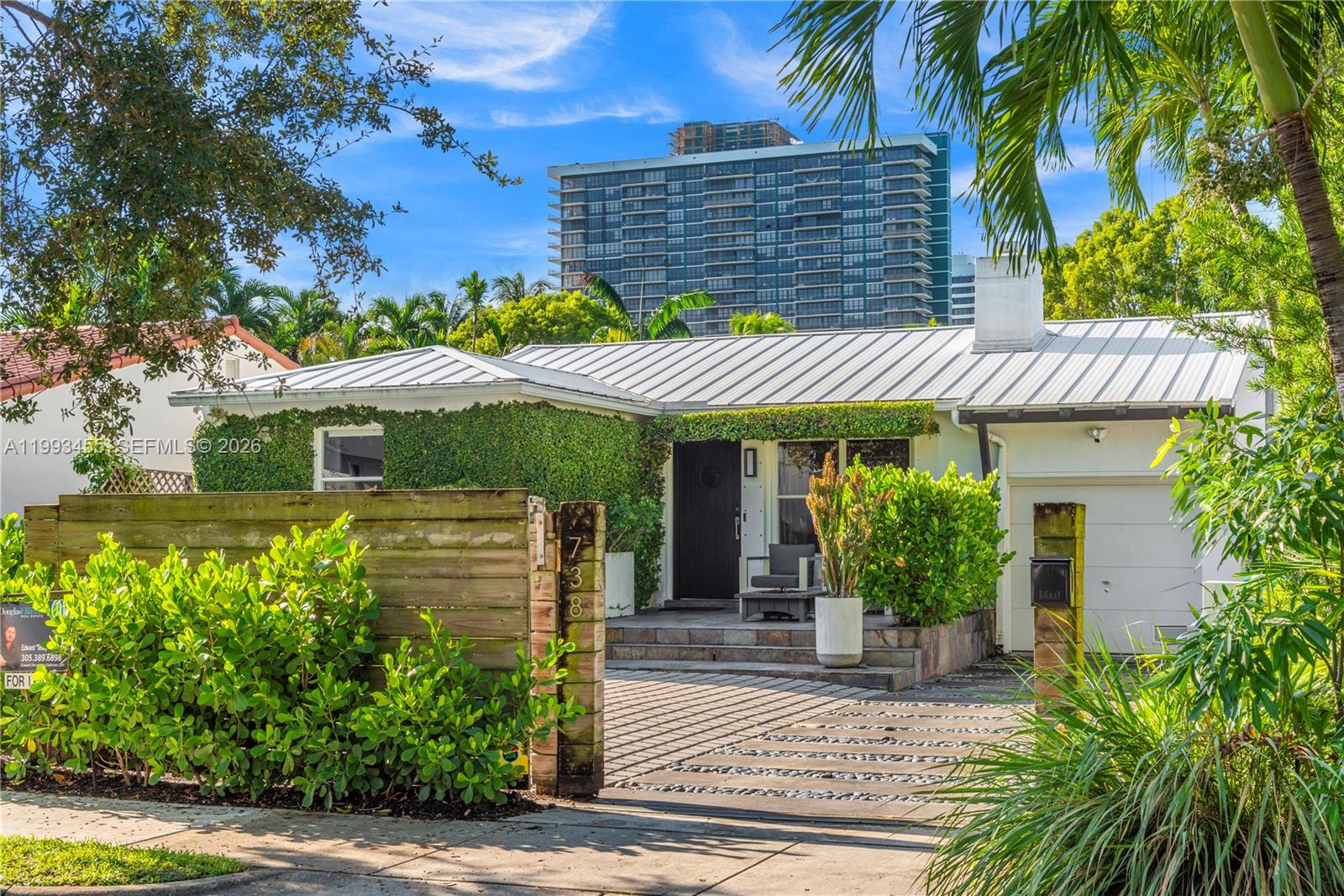 A single-story house with a metal roof, ivy-covered walls, and a paved driveway — 738 NE 72nd Ter, Miami FL 33138, MIAMI, FL