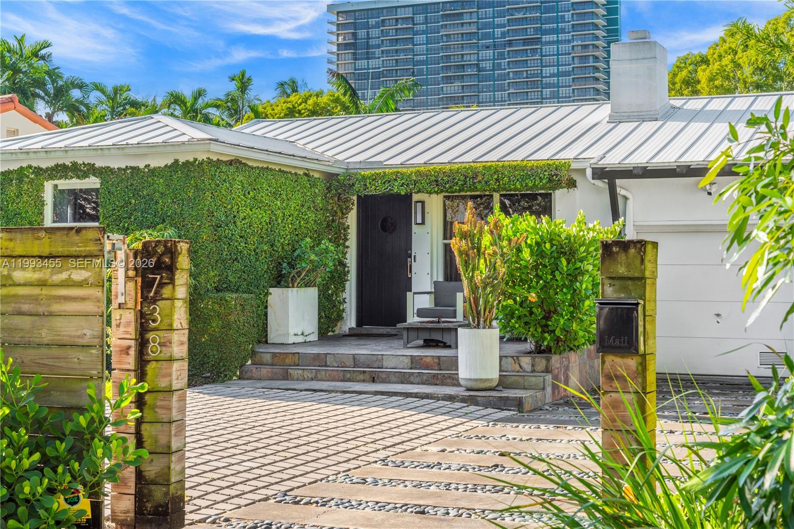 A single-story house with a metal roof, ivy-covered wall, and a paved driveway — 738 NE 72nd Ter, Miami FL 33138, MIAMI, FL