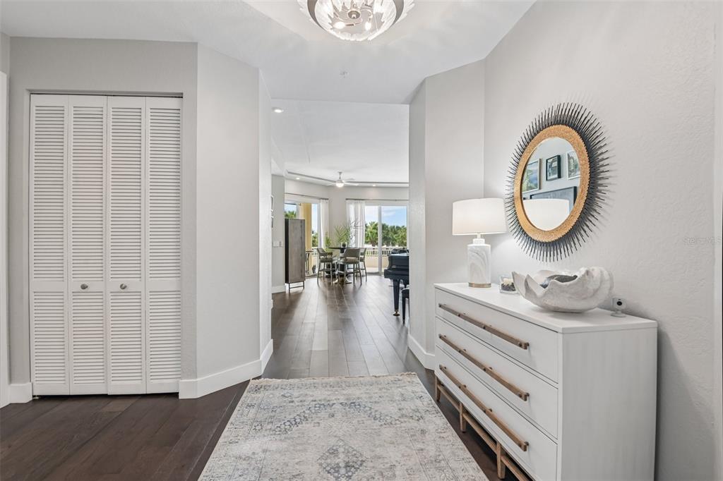 A bright entryway features a white dresser, a round mirror, and a view into a living area — 1180 GULF BOULEVARD UNIT 101, CLEARWATER BEACH, FL