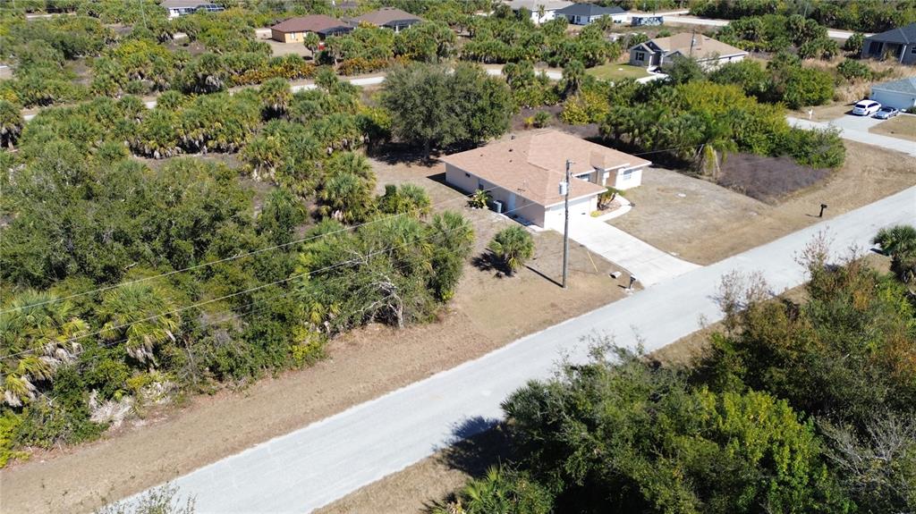 An aerial view shows a single-story house with a tan roof surrounded by dense vegetation — 13444 CEDAR CITY AVENUE, PORT CHARLOTTE, FL