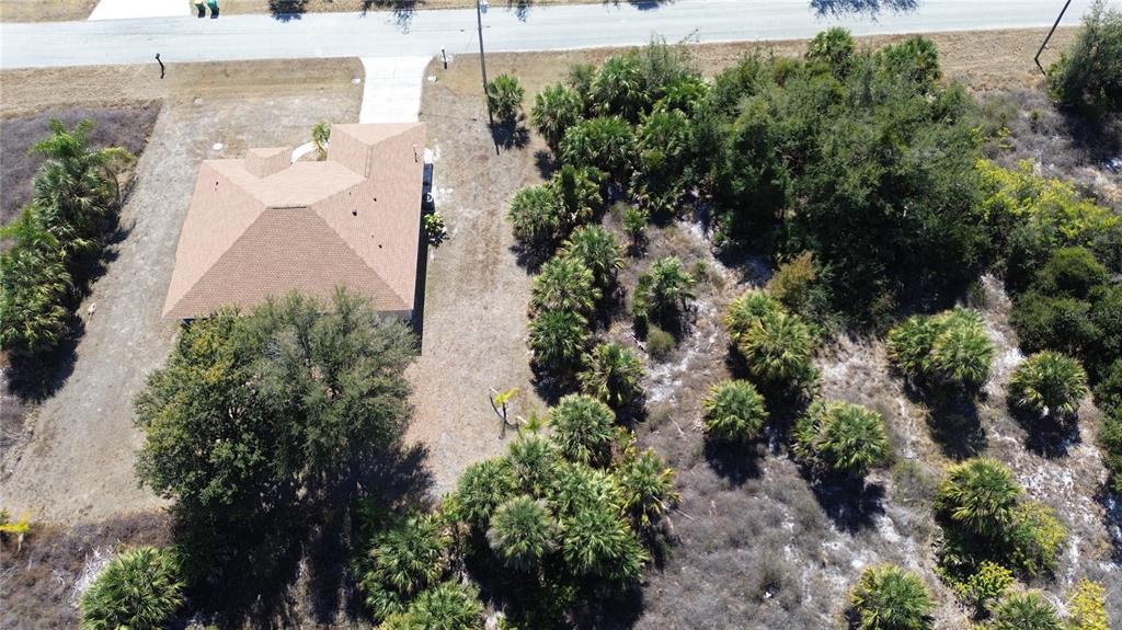 An aerial view shows a house with a brown roof situated on a large, wooded lot — 13444 CEDAR CITY AVENUE, PORT CHARLOTTE, FL