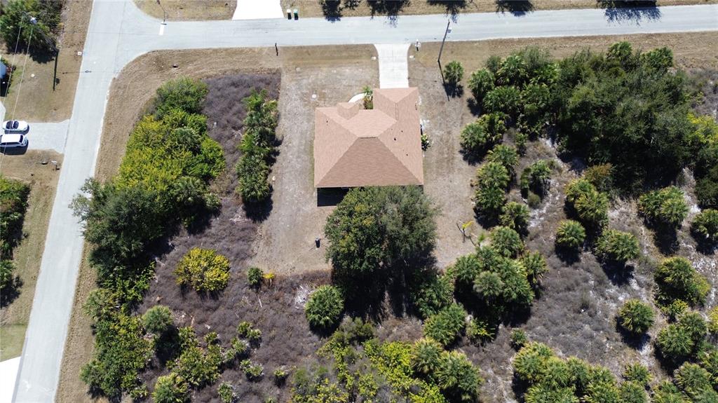 An aerial view shows a single-story house with a brown roof situated on a wooded lot — 13444 CEDAR CITY AVENUE, PORT CHARLOTTE, FL