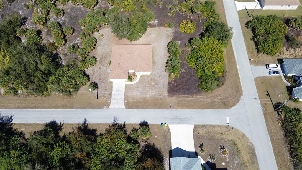 An aerial view shows a single-story house with a driveway situated on a corner lot — 13444 CEDAR CITY AVENUE, PORT CHARLOTTE, FL