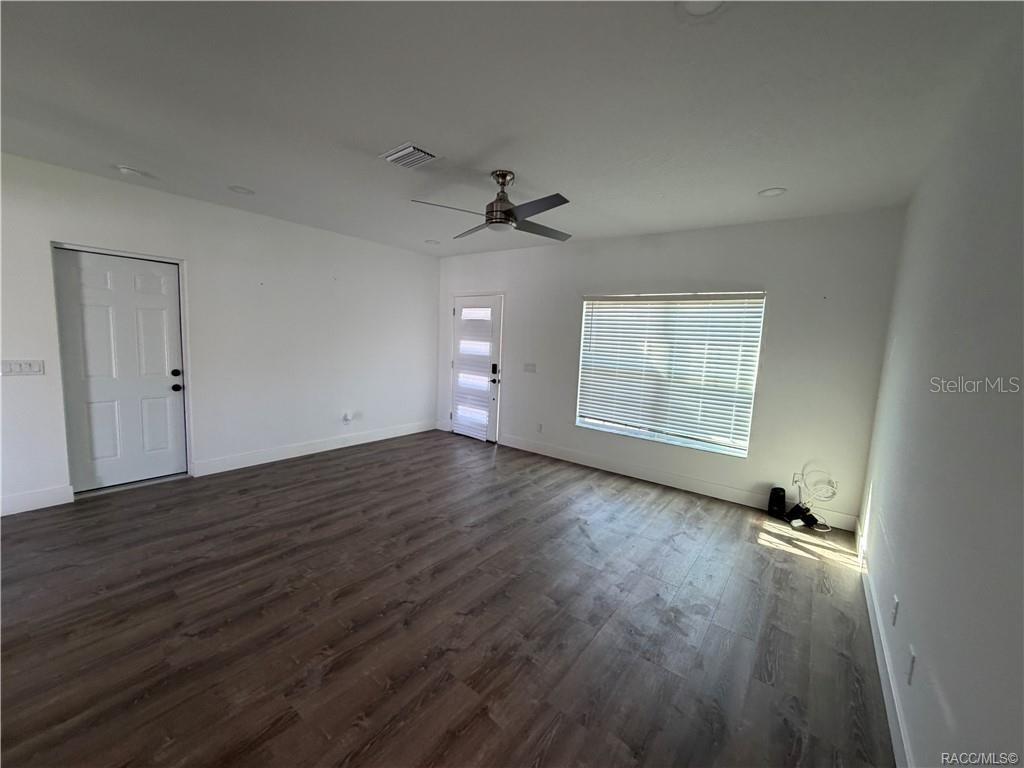 An empty room features white walls, dark wood-look flooring, a ceiling fan, and two doors — 5737 N CLAREMONT DRIVE, CITRUS SPRINGS, FL