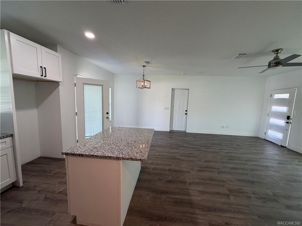 A kitchen with a granite island, white cabinets, and wood-look flooring in an open space — 5737 N CLAREMONT DRIVE, CITRUS SPRINGS, FL
