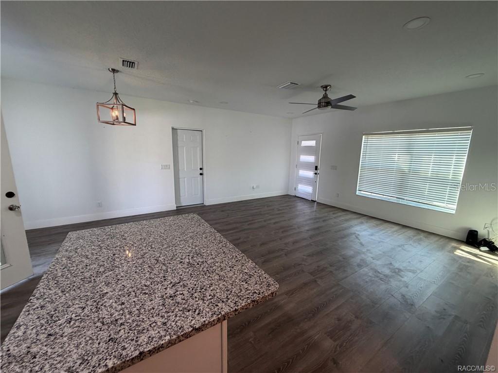 An open-concept living area features wood-look flooring, a granite-topped kitchen island, and a ceiling fan — 5737 N CLAREMONT DRIVE, CITRUS SPRINGS, FL