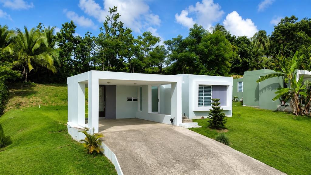A modern, white single-story house features a prominent carport and a concrete driveway — 115 km 13.2 BO PUEBLO, RINCON, PR