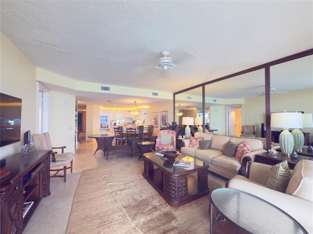 A living room features a large mirror wall, beige sofa, and an open dining area — 800 Ocean Drive # 404, Juno Beach FL 33408, JUNO BEACH, FL