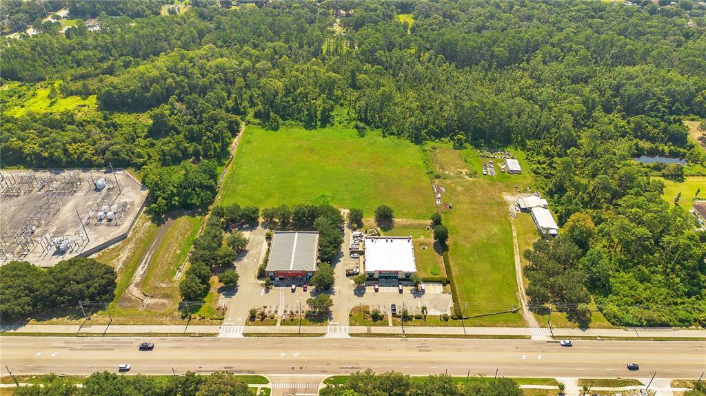 An aerial view shows a large, rectangular grassy lot bordered by dense trees and vegetation — ROCK SPRINGS ROAD, APOPKA, FL
